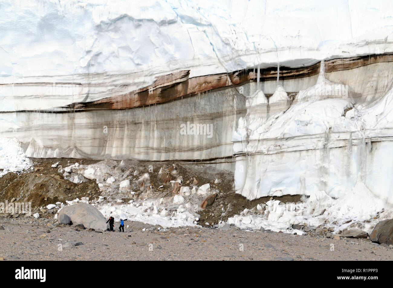 Layers of red color from iron deposits within glacier associated with Blood Falls at Taylor Valley, McMurdo Dry Valleys, Antarctica with 2 people Stock Photo