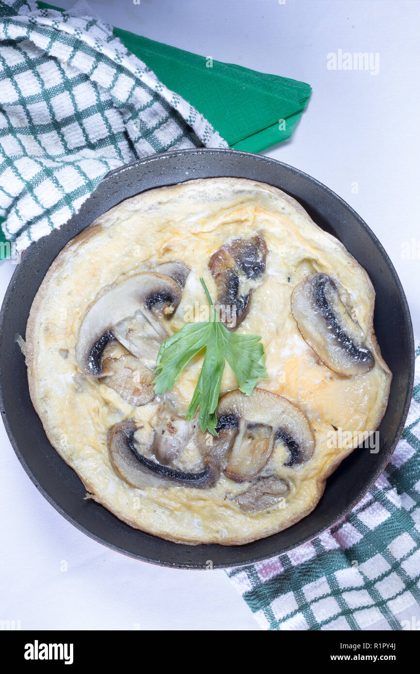 A mushroom omelette cooking in a shallow frying pan/skillet Stock Photo
