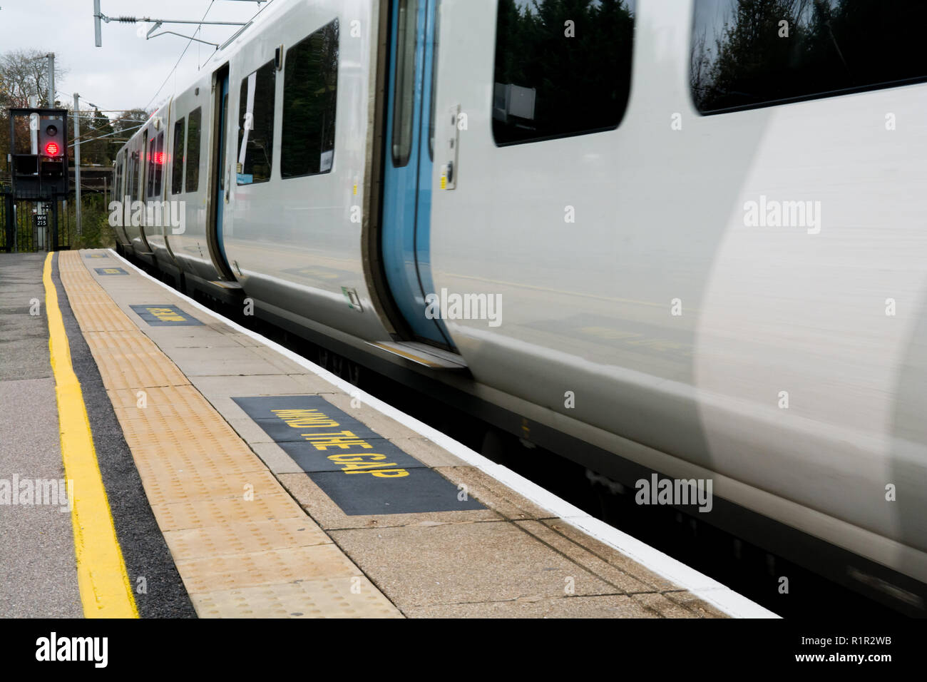 Train moving away from the platform at the rail station Stock Photo