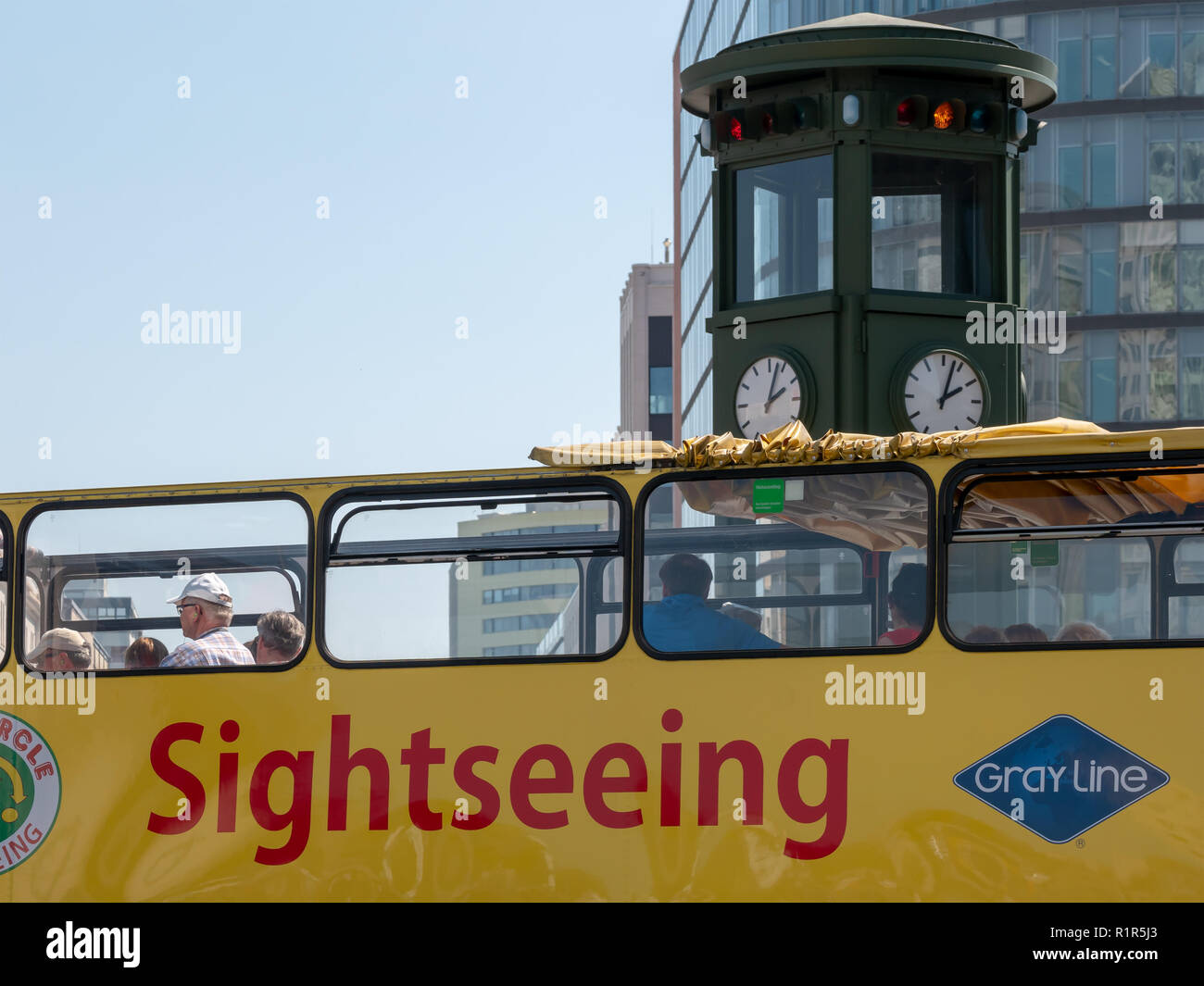 BERLIN, GERMANY - AUGUST 3, 2018: Yellow Tourist Bus At Famous Potsdamer Platz Square With Clock In Background In Berlin, Germany Stock Photo