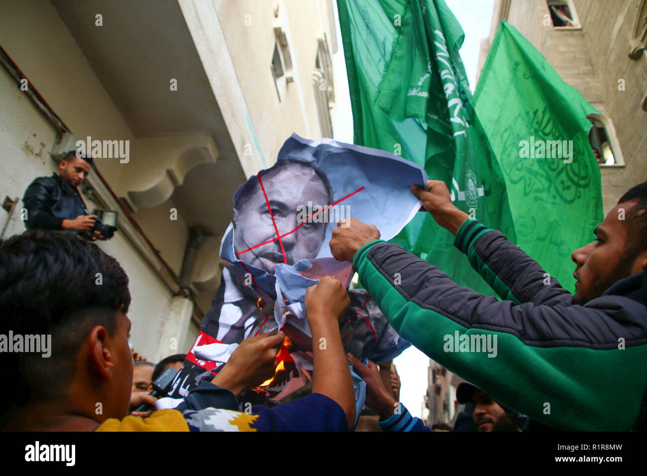 Palestinian demonstrators burn a picture of Israeli Defense Minister Avigdor Lieberman in front of the house of Ismail Haniyeh, head of the Palestinian Hamas movement in Gaza city. Hundreds of Gaza Palestinians gathered in front of the house of the Hamas leader Ismail Haniyeh to show support to the Hamas government and protest against the decision of the air strike made by the Israeli Defense Minister Avigdor Lieberman which has caused wide spread infrastructure damage and civilian deaths. Stock Photo