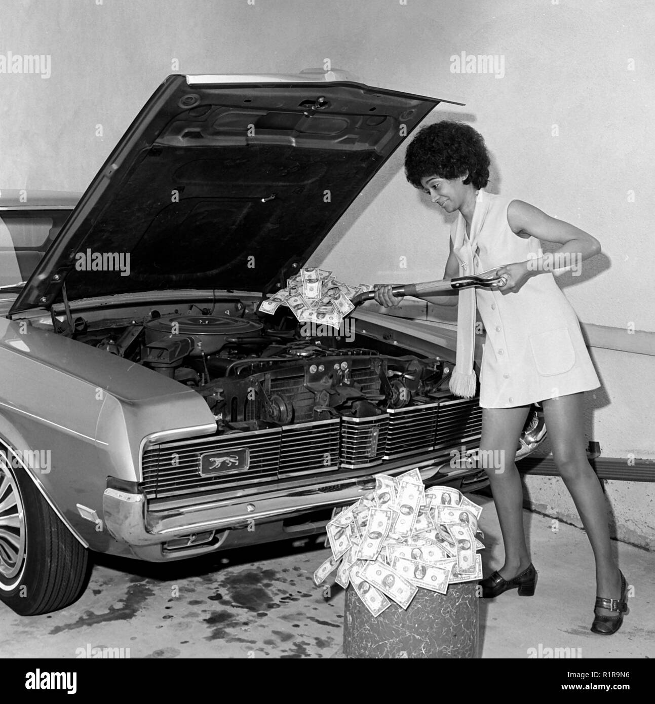 A woman shovels money into car repair, ca. 1971. Stock Photo