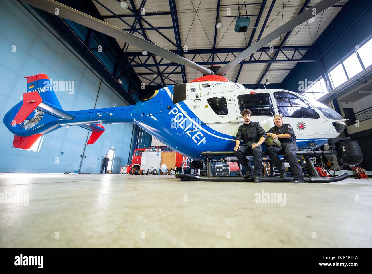 Rastede, Germany. 14th Nov, 2018. Kirsten Böning and Immo Graß - both helicopter pilots of the police of Lower Saxony, are sitting on the landing gear of a police helicopter. Credit: Mohssen Assanimoghaddam/dpa/Alamy Live News Stock Photo