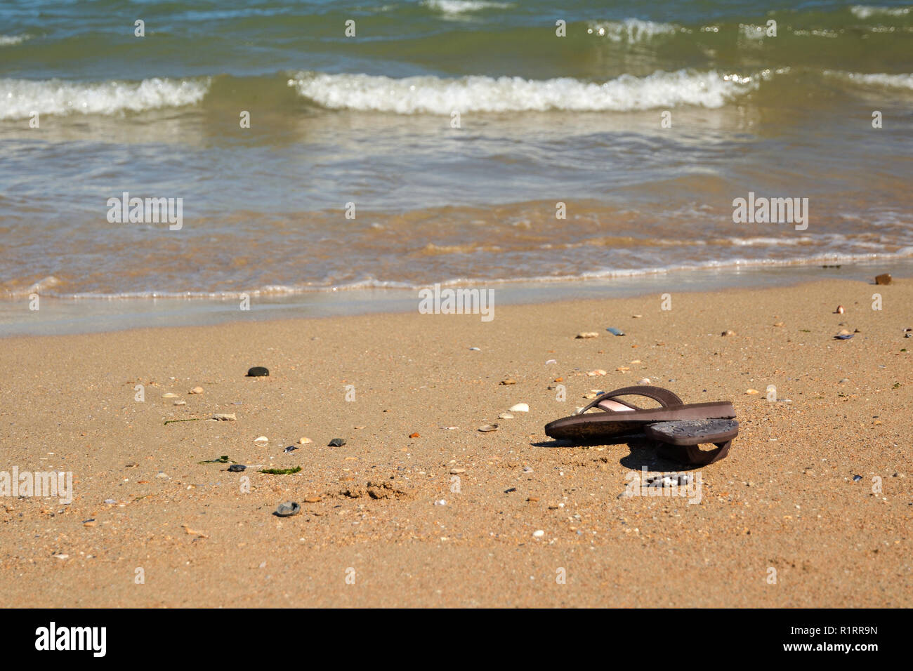 Sandals lying on one of the beaches of Nornandy. Owner is probably enjoying cold sea Stock Photo