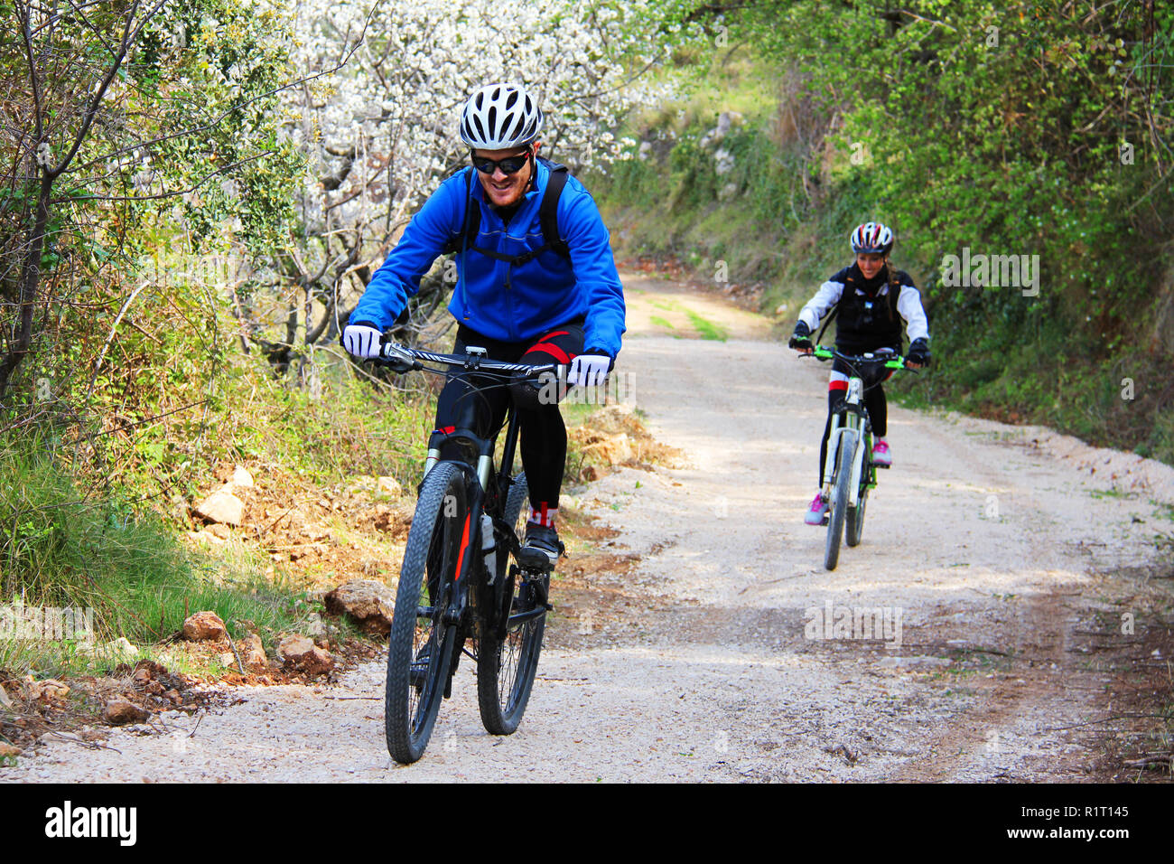 Young couple riding a bike in a forest trail Stock Photo - Alamy