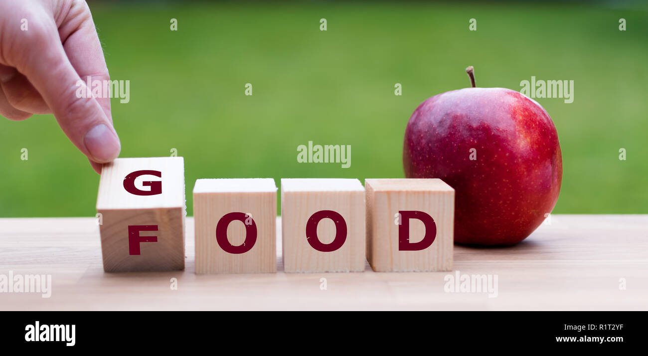 Hand is turning a dice and changes the word 'good' to 'food' Stock Photo