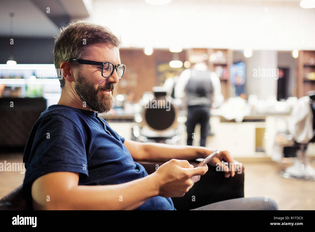 Hipster man client visiting haidresser and hairstylist in barber shop, waiting. Stock Photo