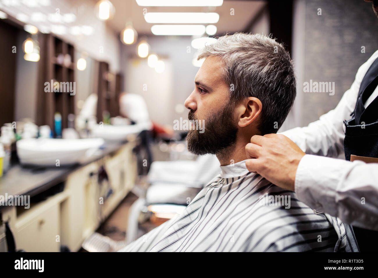 Hipster man client visiting haidresser and hairstylist in barber shop. Stock Photo