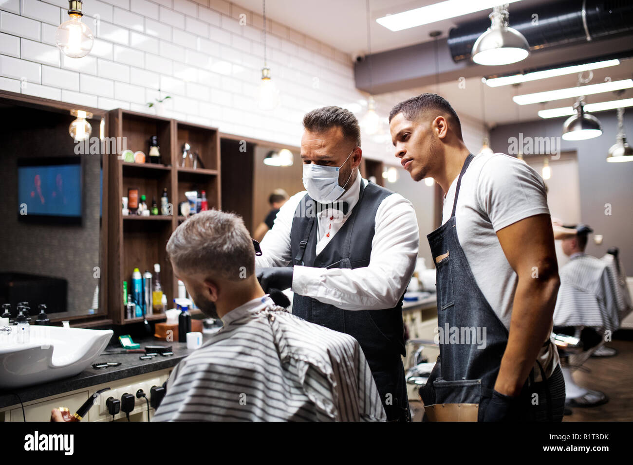 Hipster man client visiting haidresser and hairstylist in barber shop, training concept. Stock Photo
