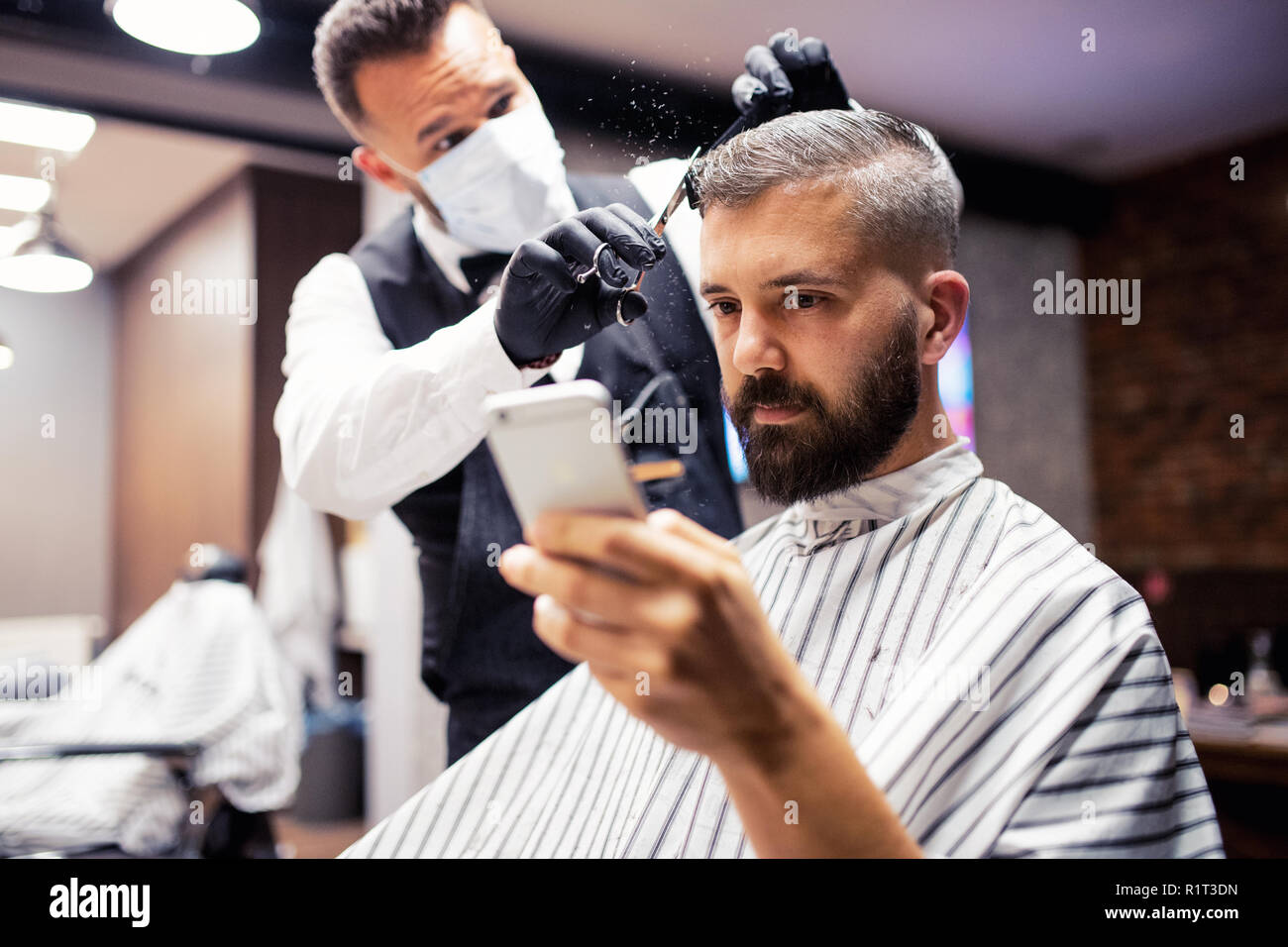 Hipster man client visiting haidresser and hairstylist in barber shop, taking selfie. Stock Photo