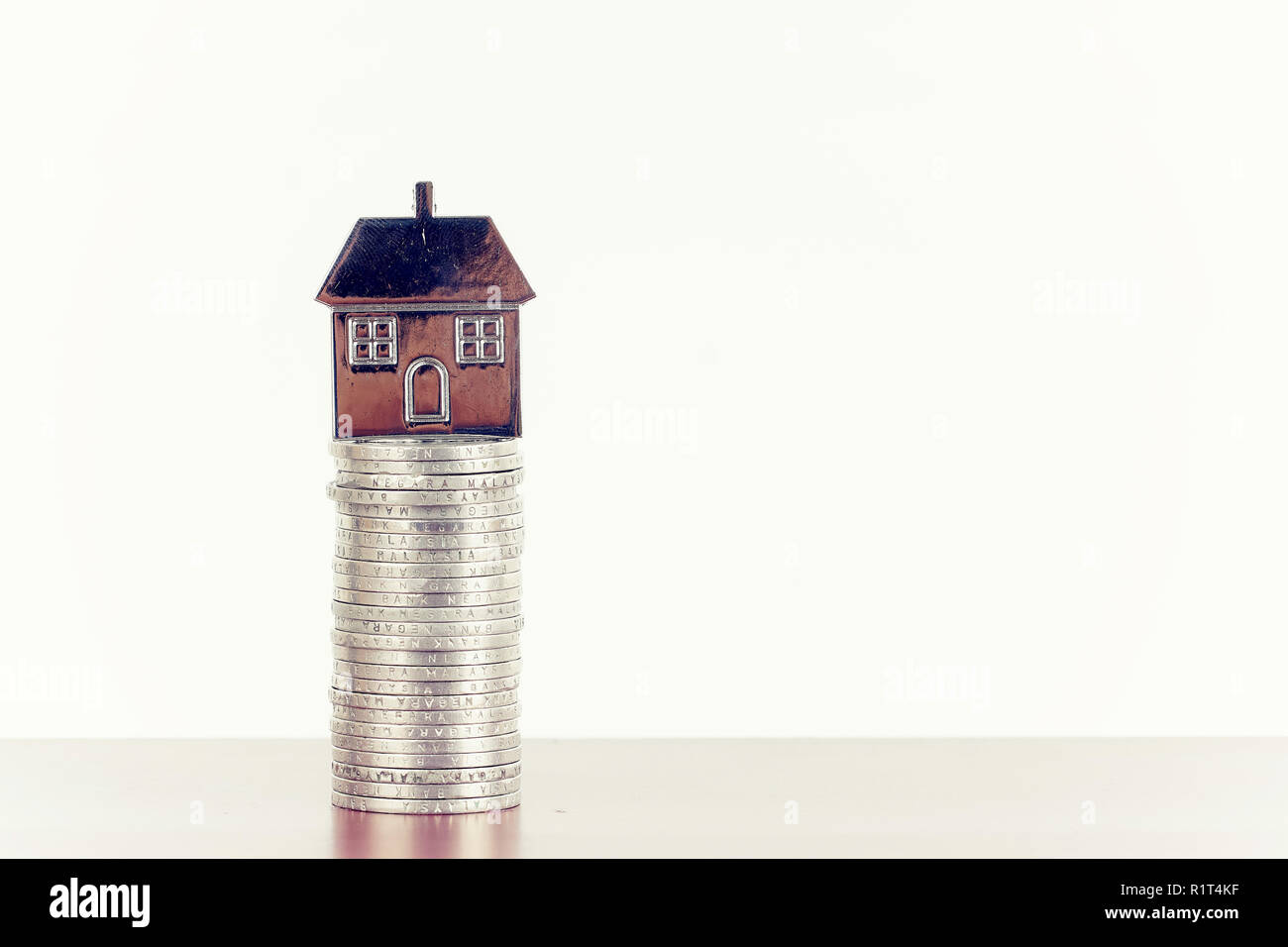 stack of coins and metal house replica for property investment concept Stock Photo