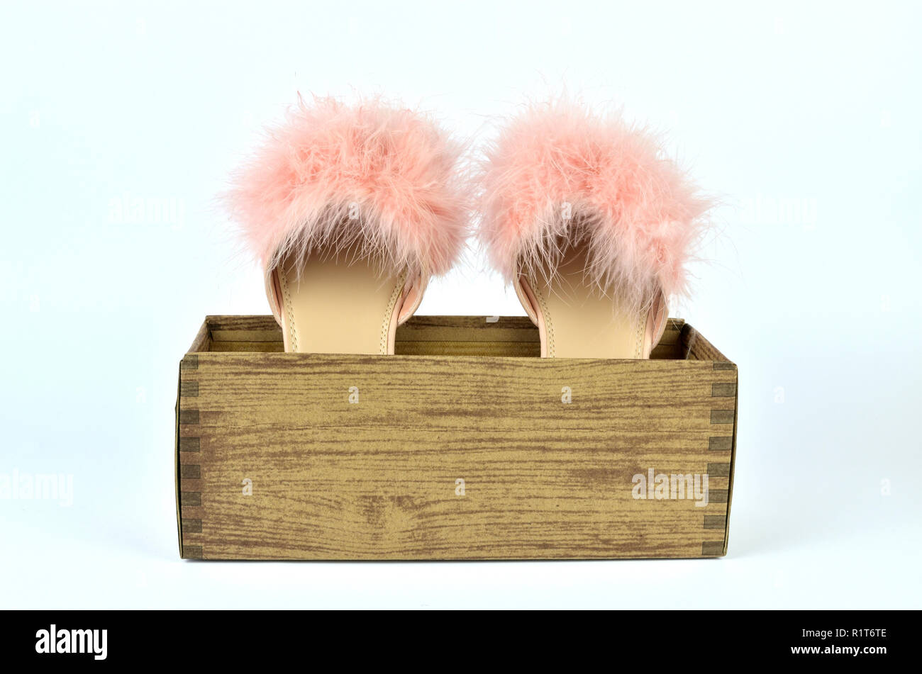 Pink feather slippers in a cardboard box with wooden pattern Stock