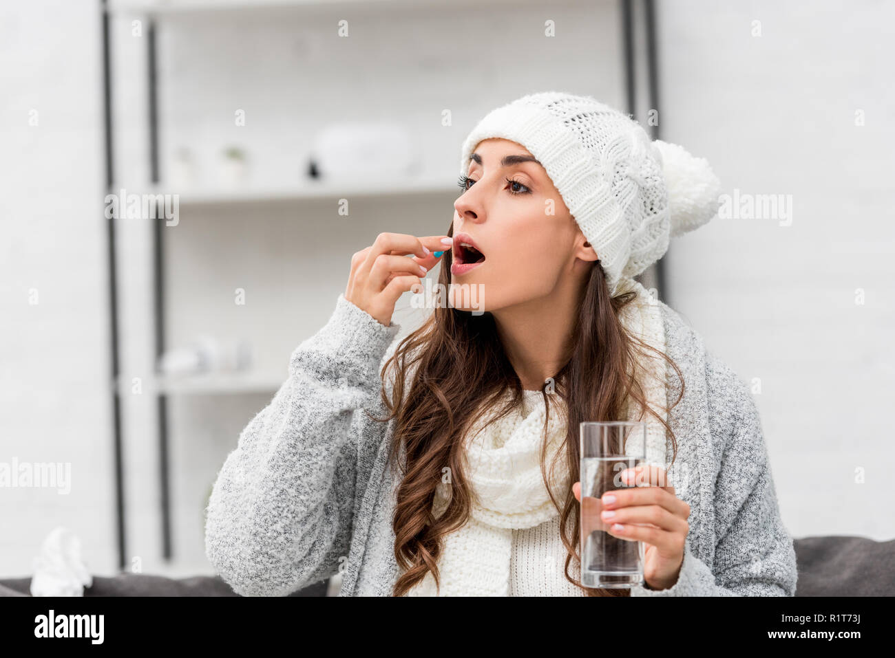 Close Up Portrait Of Sick Young Woman In Warm Clothes Taking Pill At Home Close Up Portrait Of Sick Young Woman In Warm Clothes Taking Pill At Home