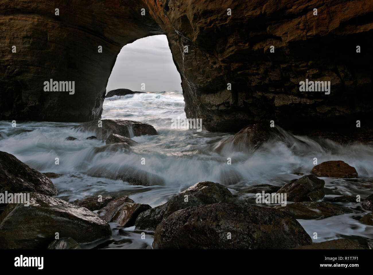 OR02384-00...OREGON - In-coming tide bring water back through the archway, into the Devil's Punchbowl; Devil's Punchbowl State National Area. Stock Photo