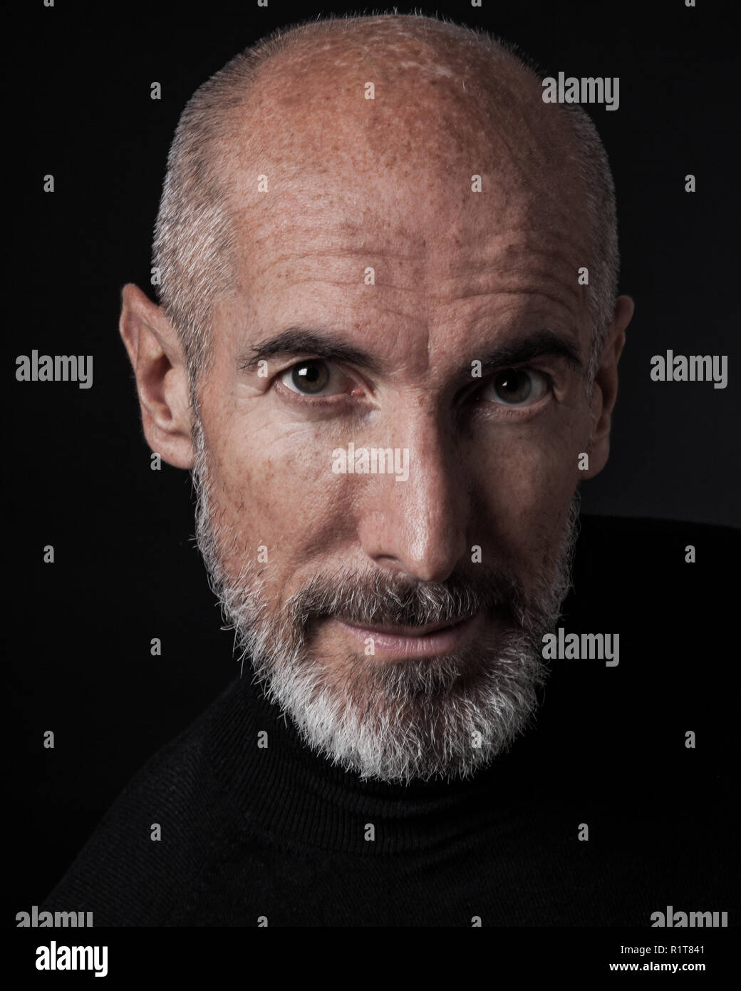 Studio portrait on black background of a mature man. Stock Photo