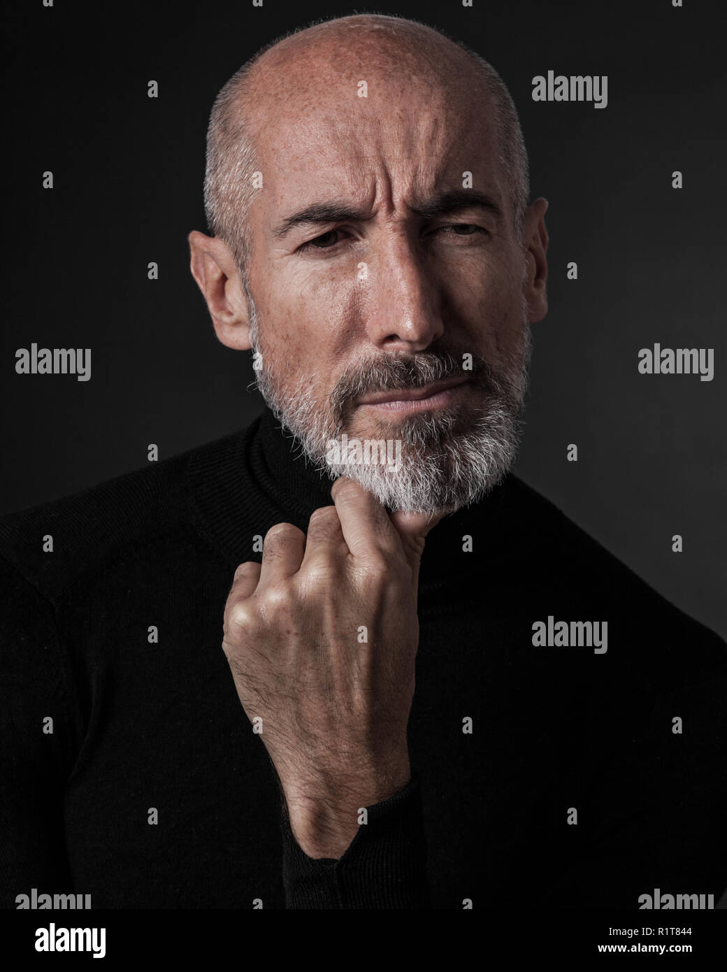 Studio portrait on black background of a mature man. Stock Photo