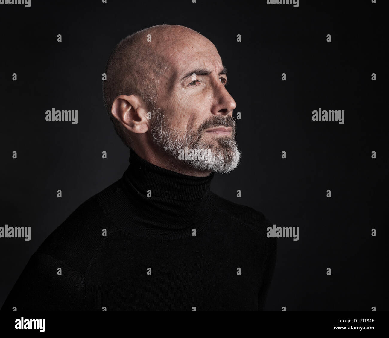 Studio portrait on black background of a mature man. Stock Photo