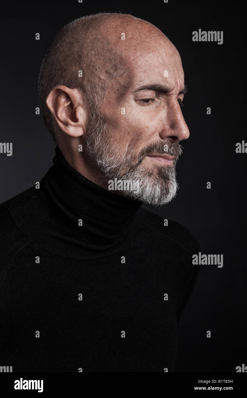 Studio portrait on black background of a mature man. Stock Photo