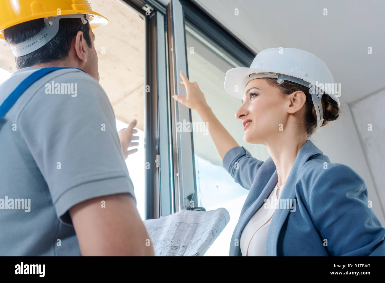 Architect woman and construction worker checking windows on site Stock Photo