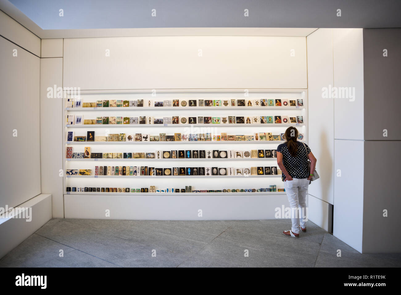 A female tourist looking at Historical books and cover of the art books displayed at Louvre Abu Dhabi, UAE Stock Photo