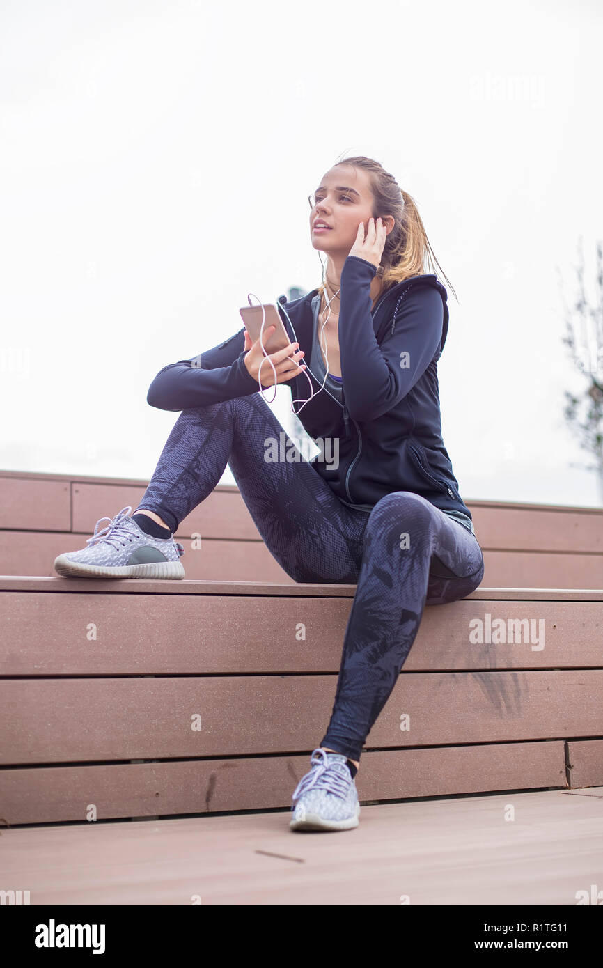 Young  fit sporty woman resting and listen music on mobile phone after  training  outdoor in urban enviroment Stock Photo