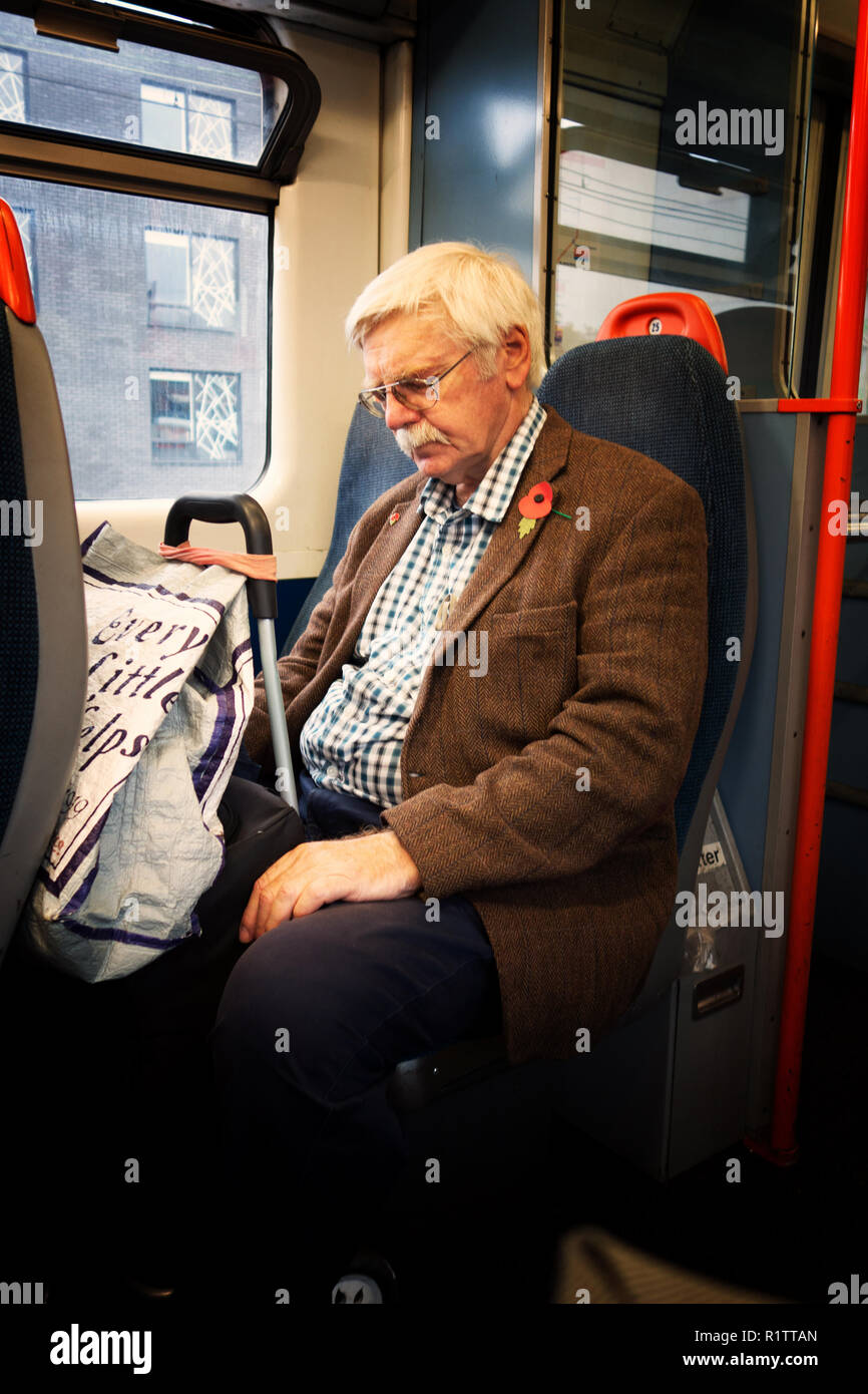 Senior man resting on his train journey on a London Overland Train Stock Photo