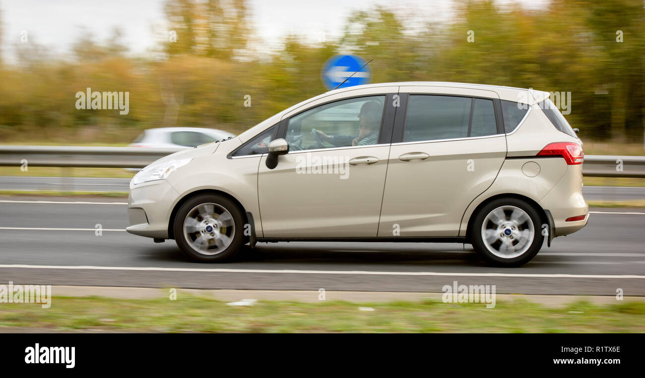 A panned shot of a beige Ford B-Max on a dual carriageway near Eastbourne, East Sussex, UK, driven by an older couple. Stock Photo