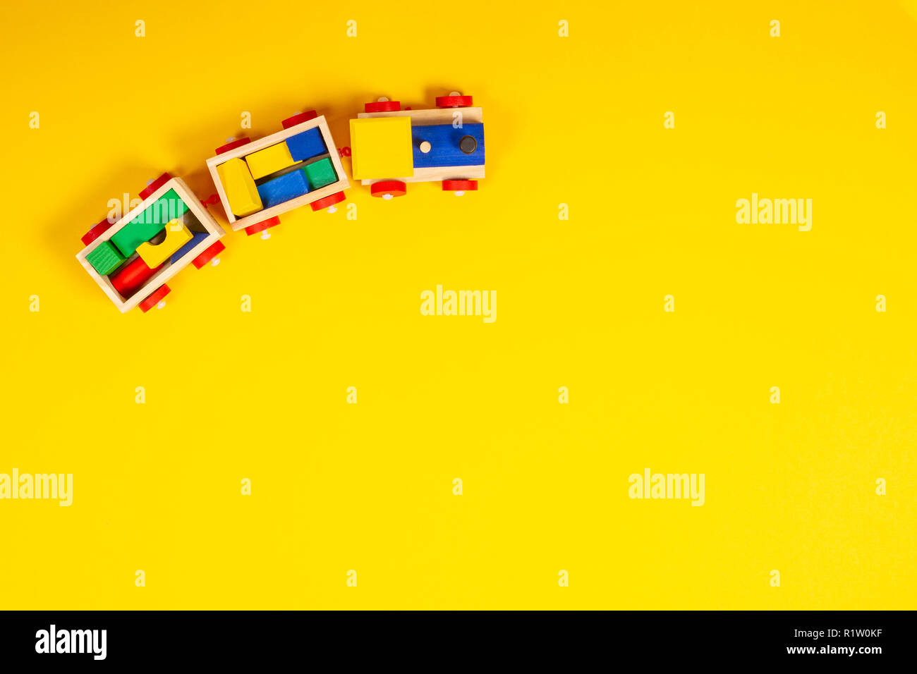 Wooden toy train with colorful blocks on yellow background Stock Photo