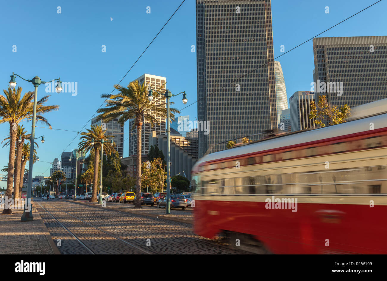 Street traffic and moving trolley car at evening rush hour in San