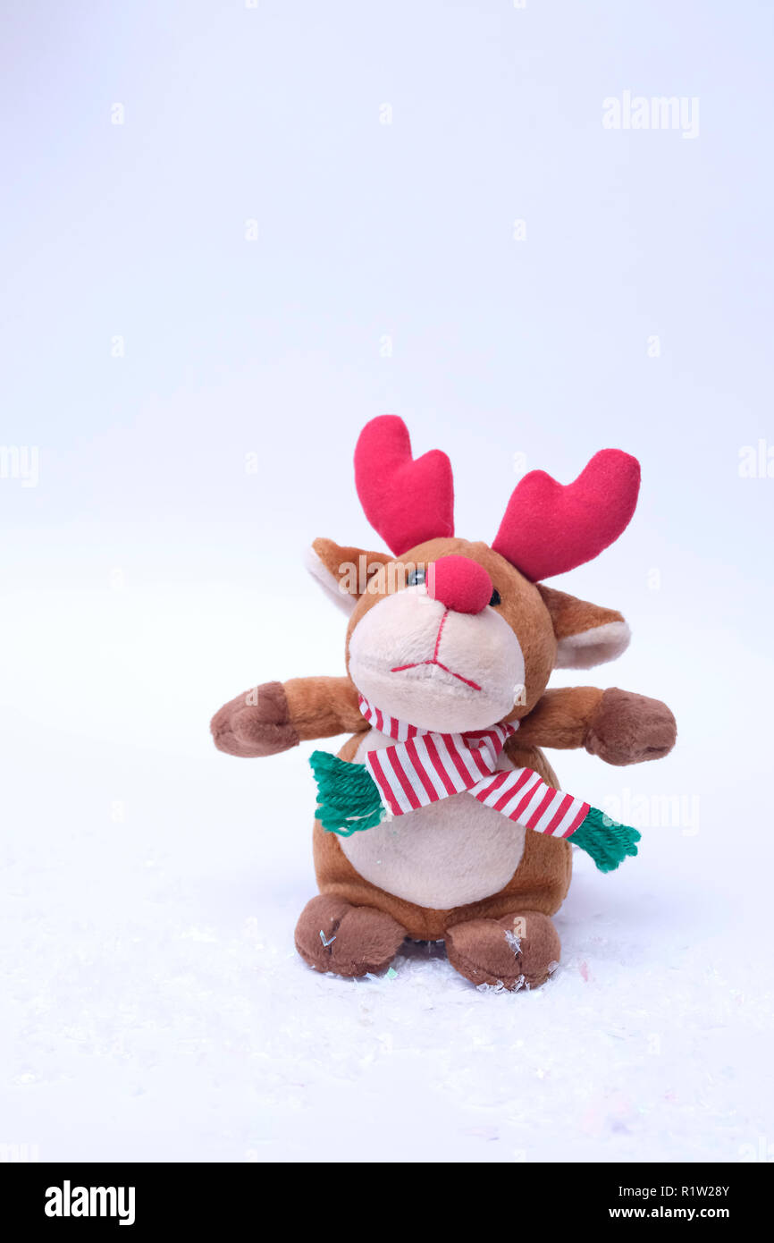 A scarf wearing Reindeer stuffed toy that has rather a sad expression on his face. Sitting on fake snow Stock Photo