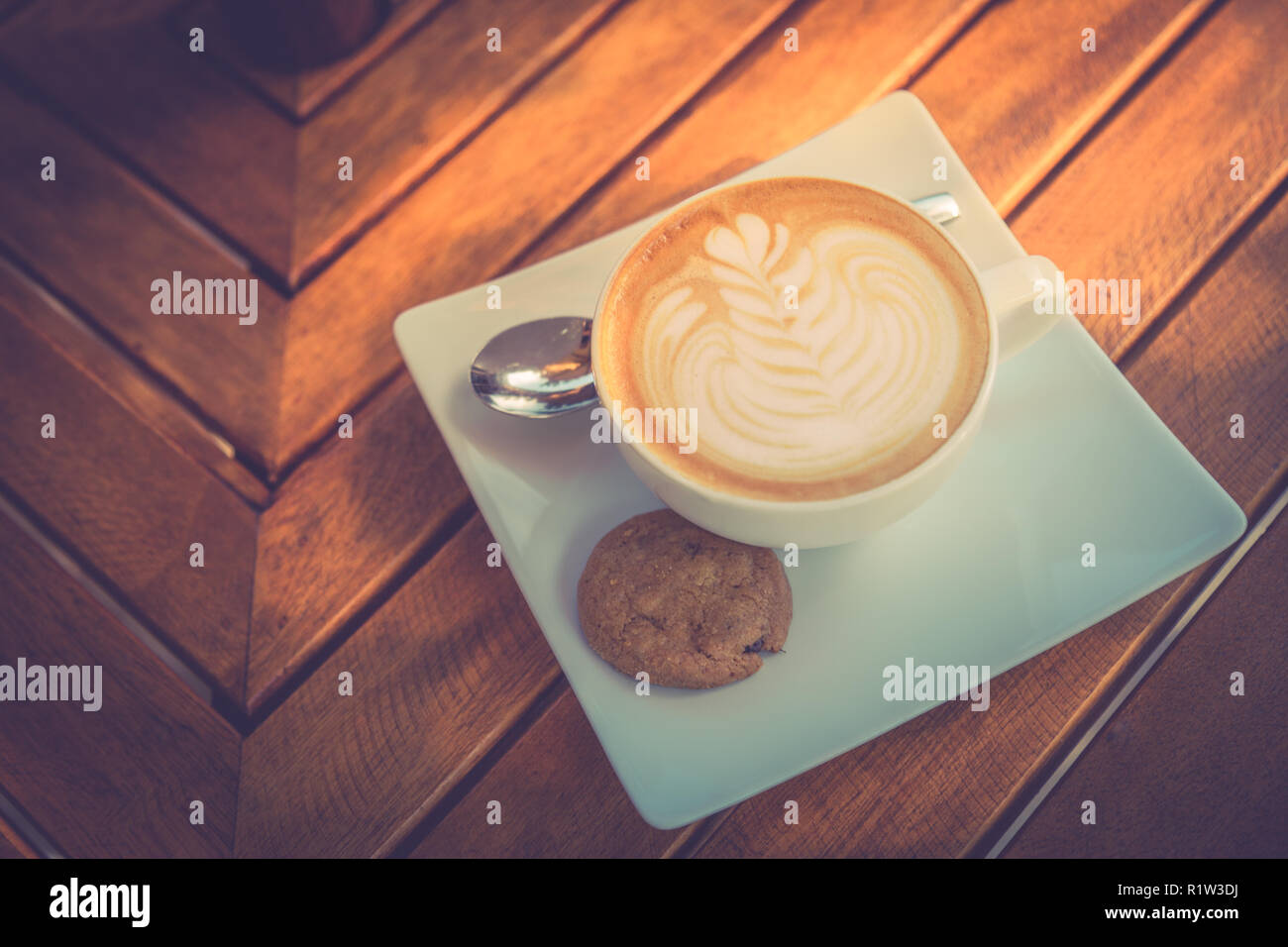 Beautiful morning wooden table top with coffee, latte art and cookie. Start the day, good mood concept. Stock Photo