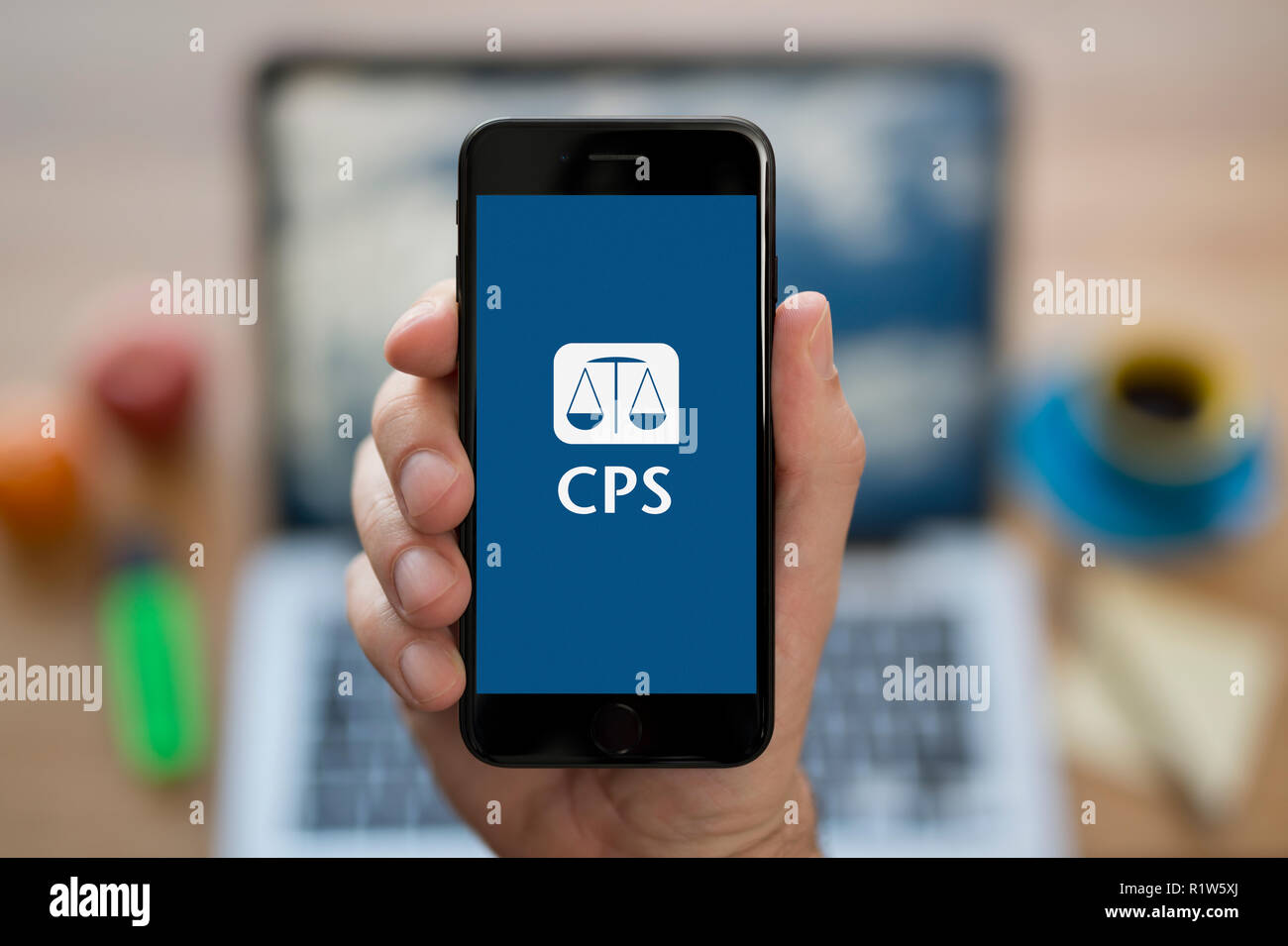 A man looks at his iPhone which displays the The Crown Prosecution