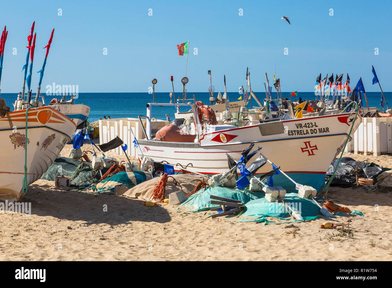 Local traditional style fishing boat with its fishing flags and floats on the beach at Monte Gordo, Algarve, Portugal Stock Photo