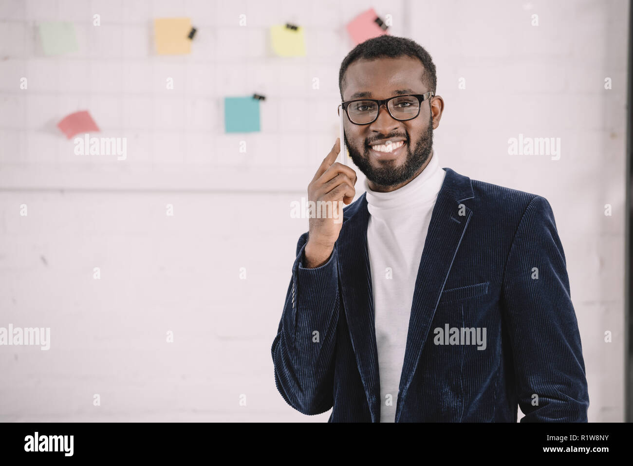 smiling african american businessman in velvet jacket talking on smartphone Stock Photo