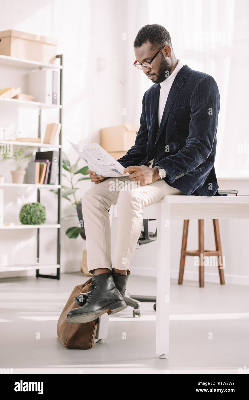 african american businessman in velvet jacket reading newspaper in modern office Stock Photo
