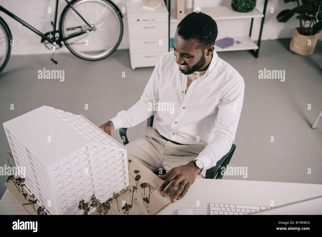high angle view of cheerful handsome african american architect looking at architecture model in office Stock Photo