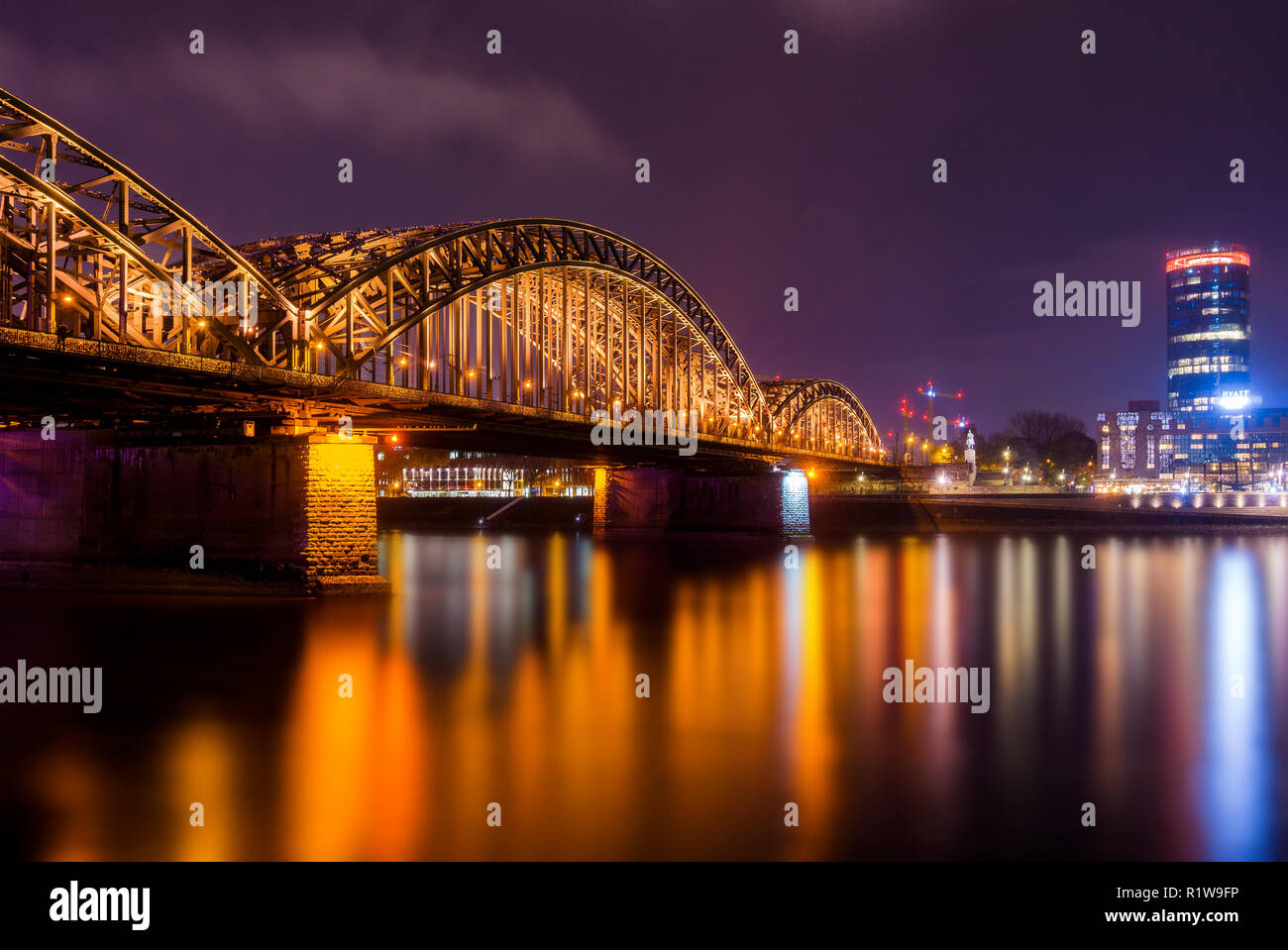 View of the Hohenzollern Bridge, the Skyscraper Cologne Triangle, the Hyatt Regency and the Long River Rhine at Night in Germany Cologne 2018. Stock Photo