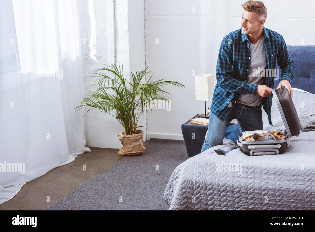 smiling male traveler packing luggage 