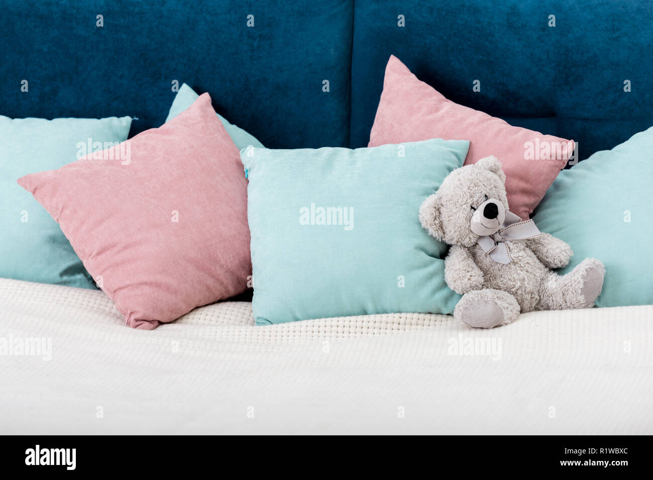 teddy bear laying on the bed with pillows on background Stock Photo