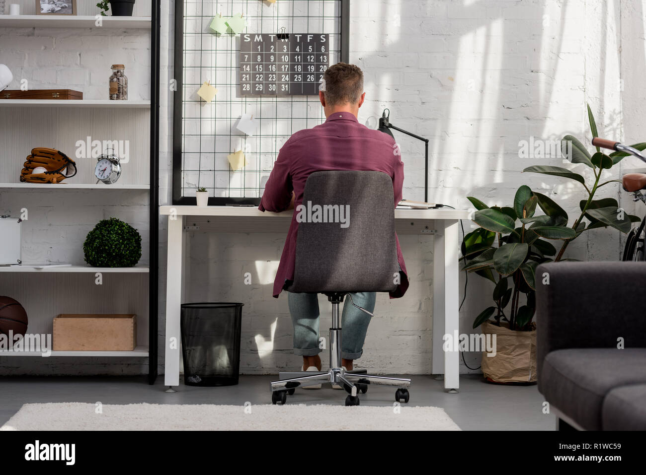 back view of man sitting on chair and working at home office Stock ...