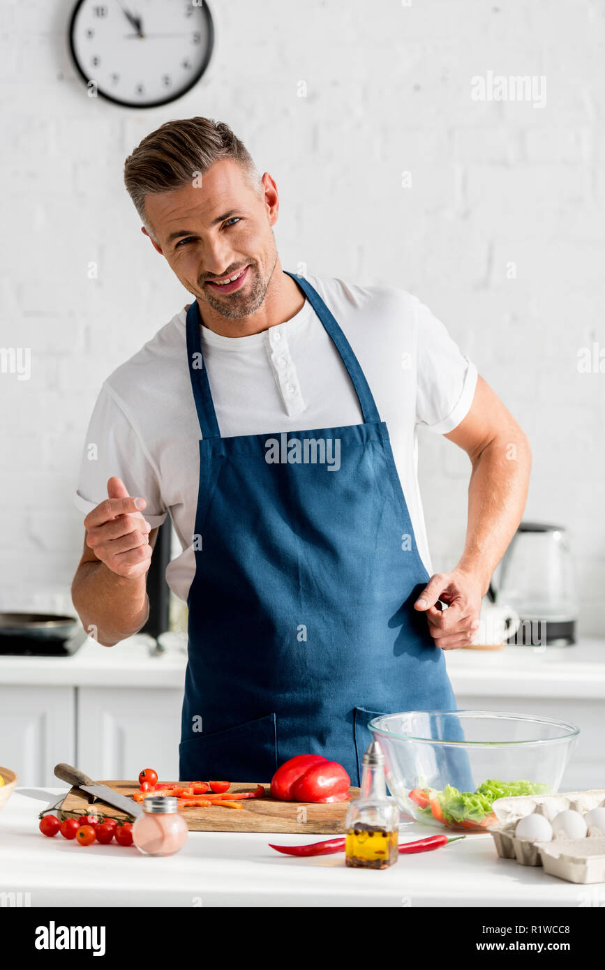 handsome smiling man in apron cooking food at kitchen Stock Photo