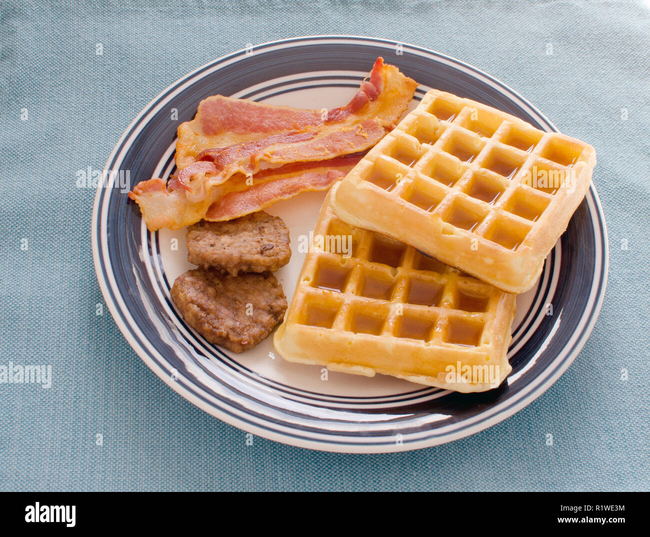 Plate of waffles with maple syrup, bacon and sausage patties Stock