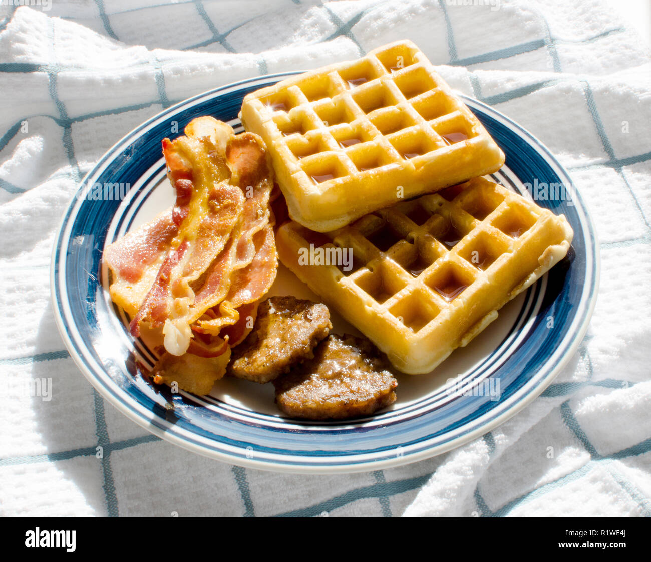 Plate of waffles with maple syrup, bacon and sausage patties Stock Photo
