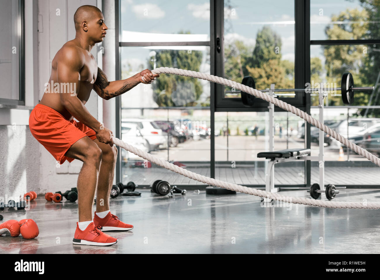 side view of african american athlete working out with battle ropes at gym Stock Photo