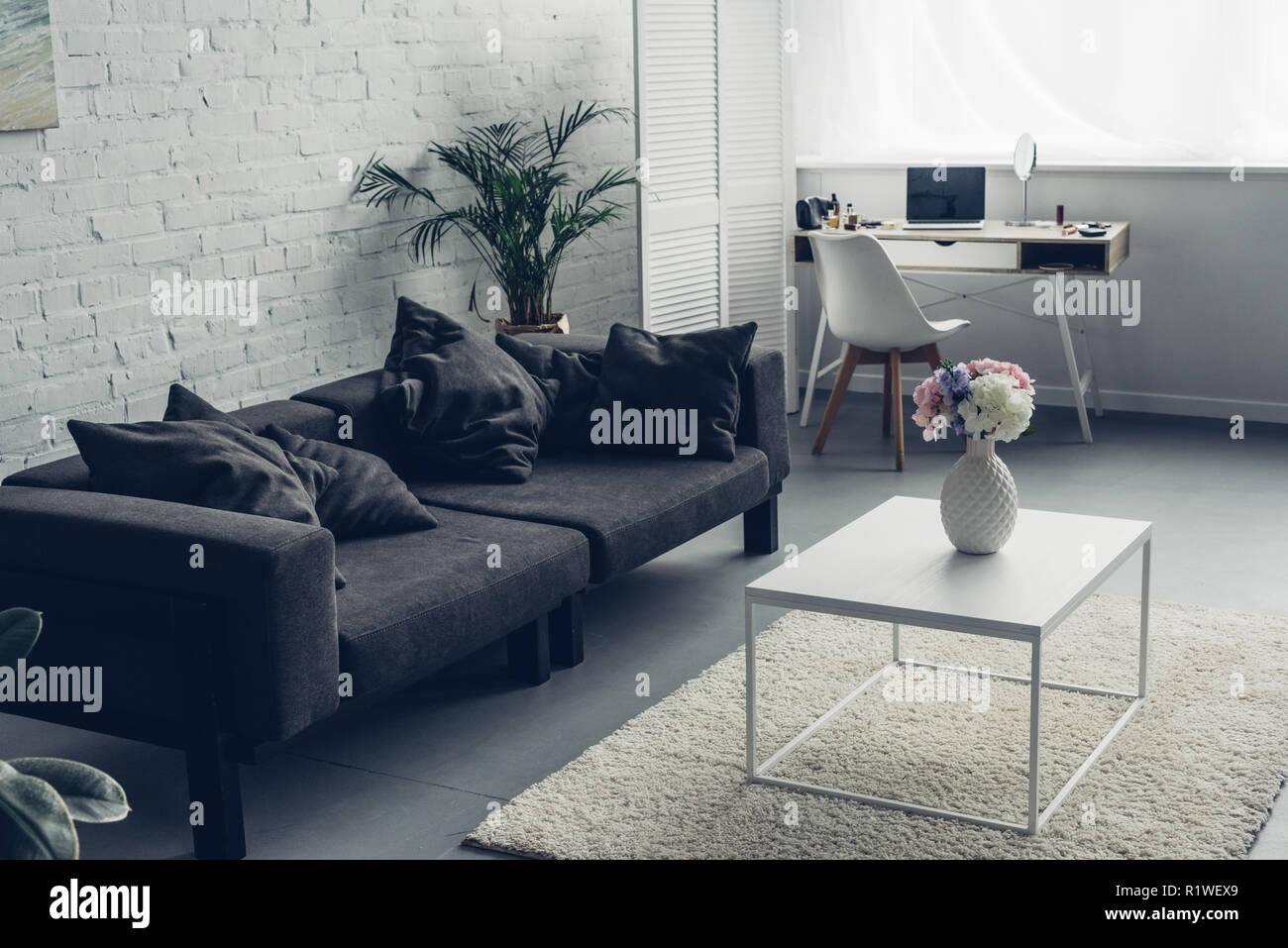 interior of modern living room with couch and workplace with laptop Stock Photo