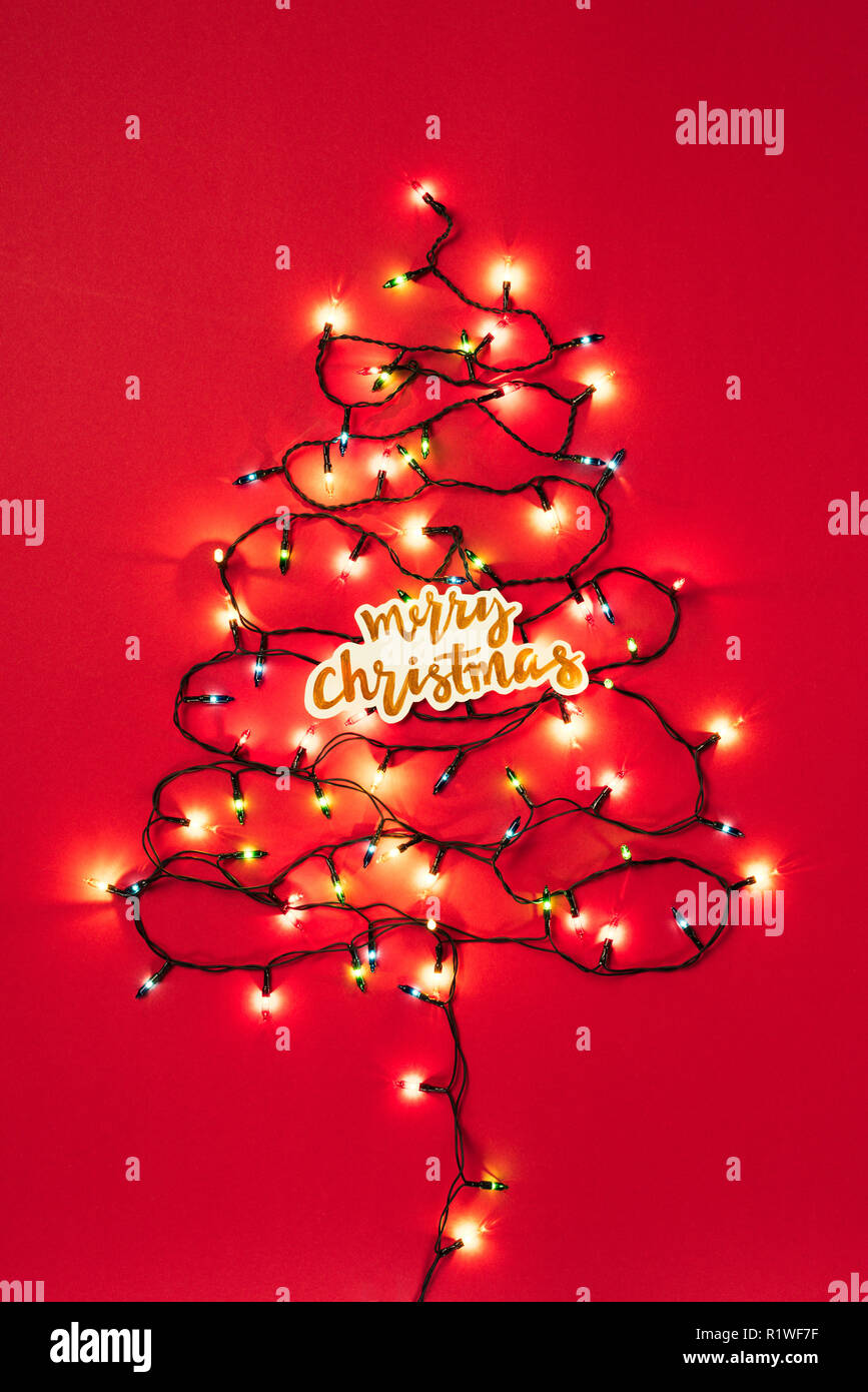 Colourful Garlands In The Form Of Christmas Tree With Merry Christmas Sign On Red Background Stock Photo Alamy
