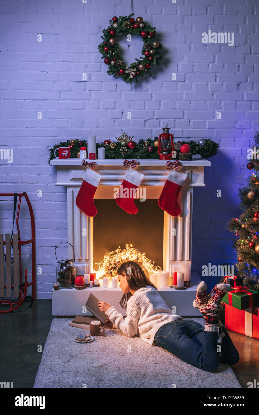 Adorable Woman Reading Near Christmas Decorated Fireplace And