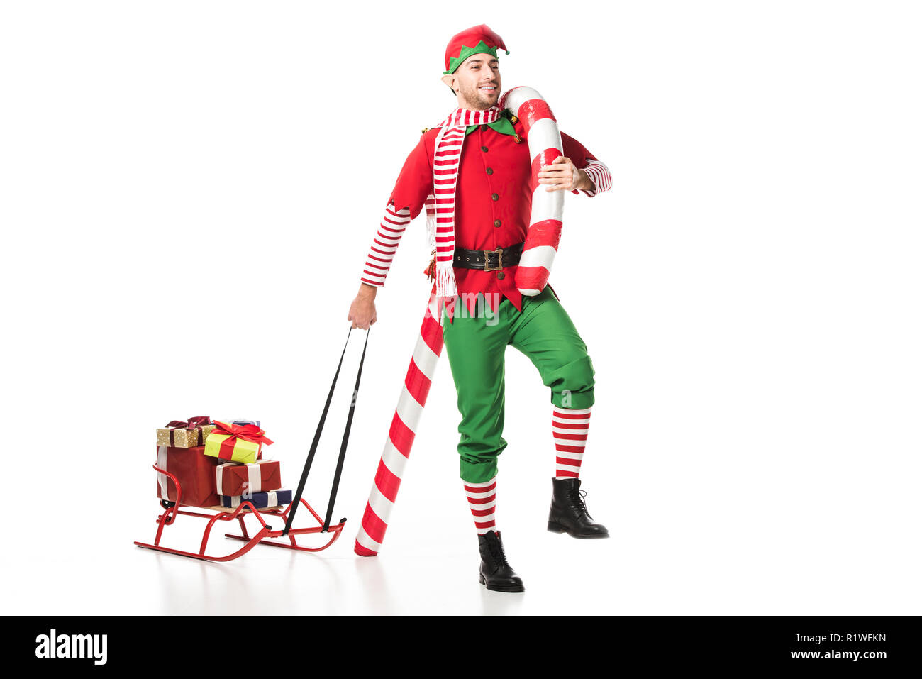smiling man in christmas elf costume carrying sleigh with presents and