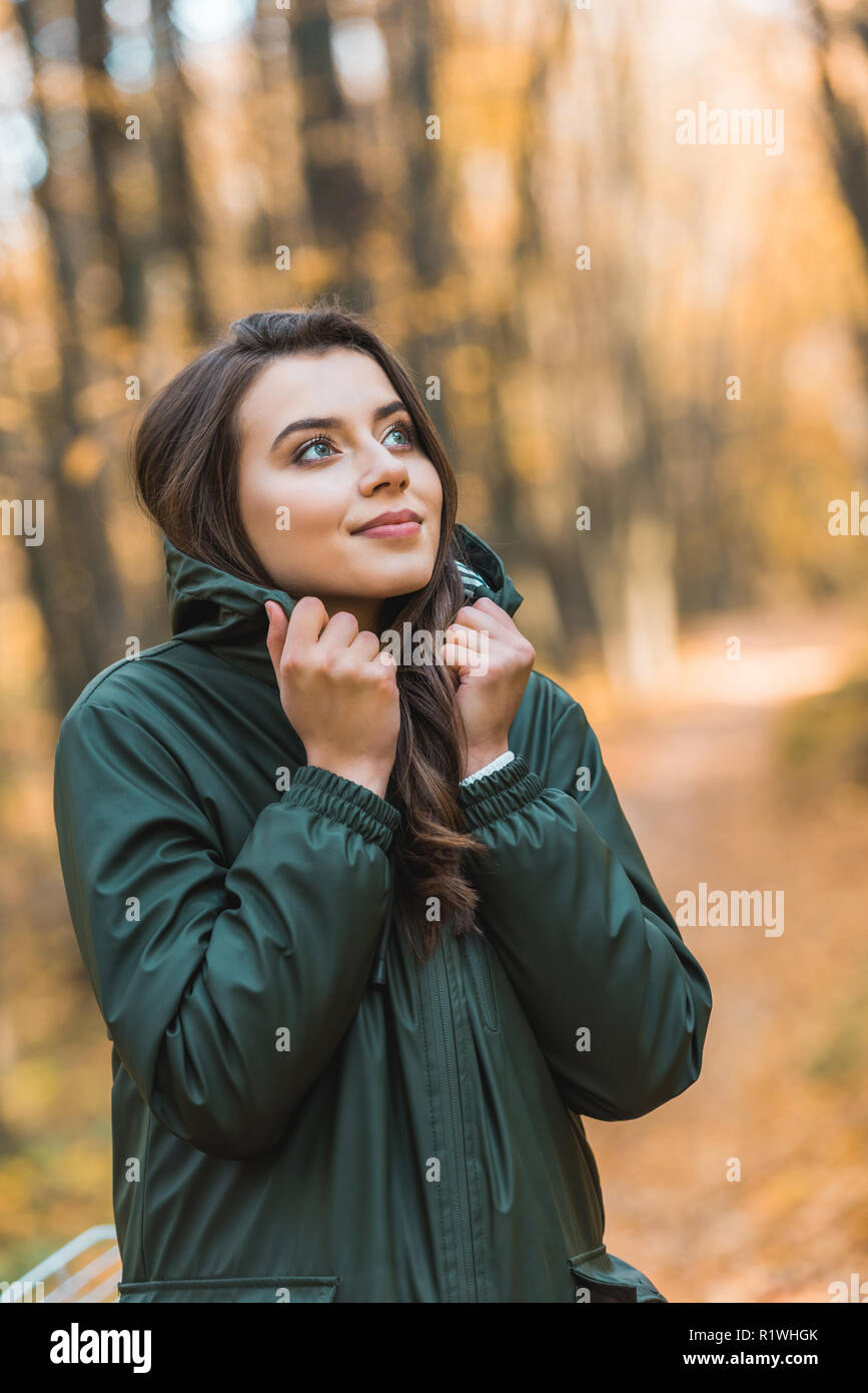 selective focus of beautiful young woman in jacket posing outdoors ...