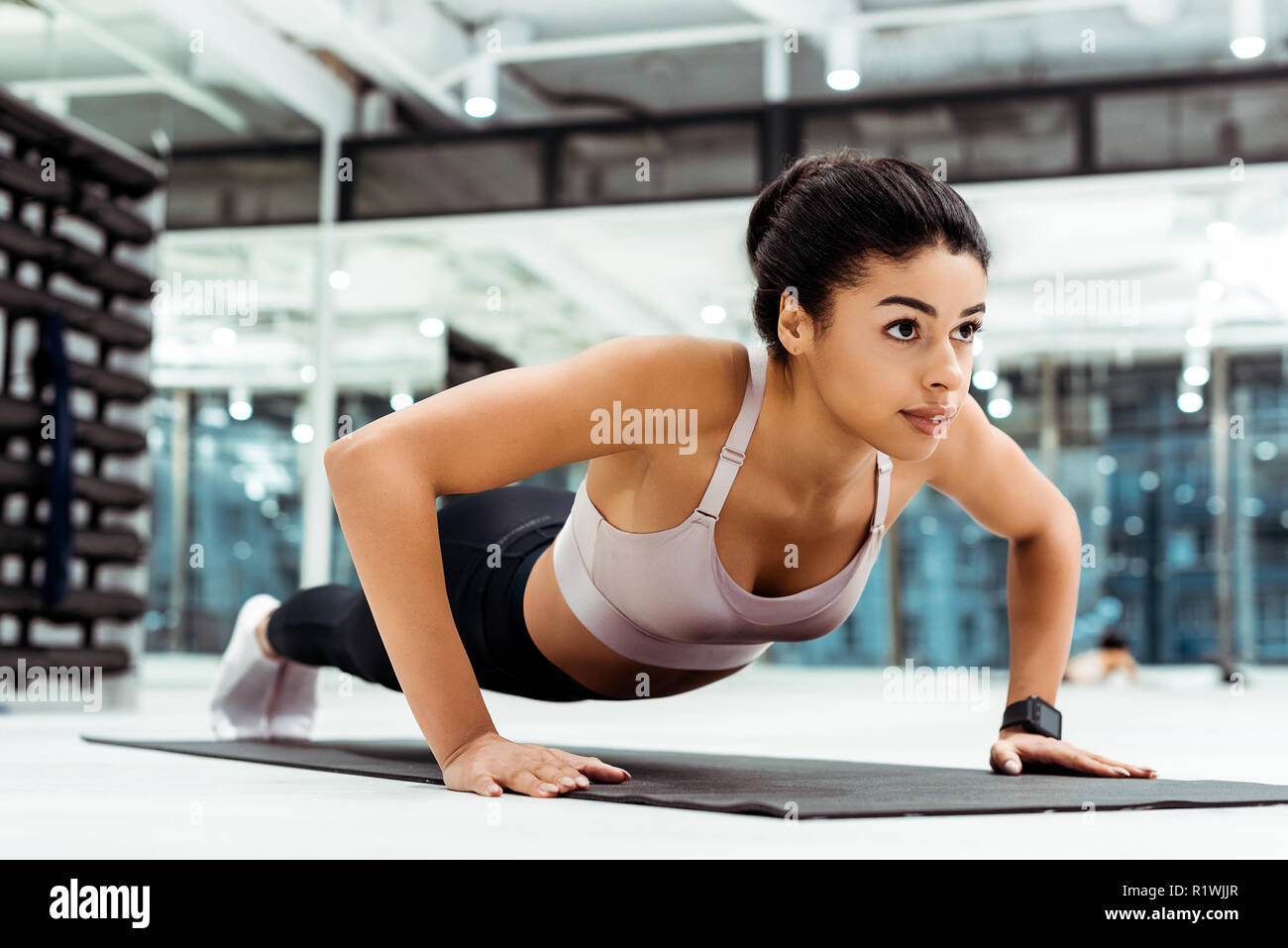 Wonderful young girl doing push ups on mat in fitness gym Stock Photo